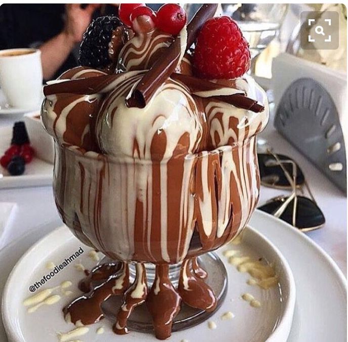 Ice cream sundae with chocolate sauce, whipped cream, strawberries and berries in a decorative glass dish
