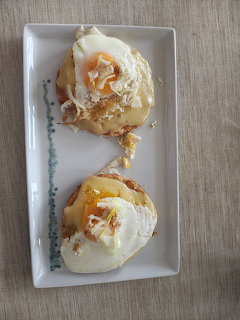 Two eggs Benedict on a white rectangular plate on a wooden table