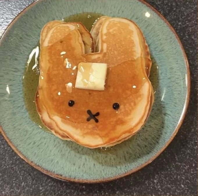Bunny-shaped pancake with butter and syrup on a blue plate