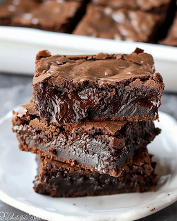Stack of four chocolate fudge brownies on white plate