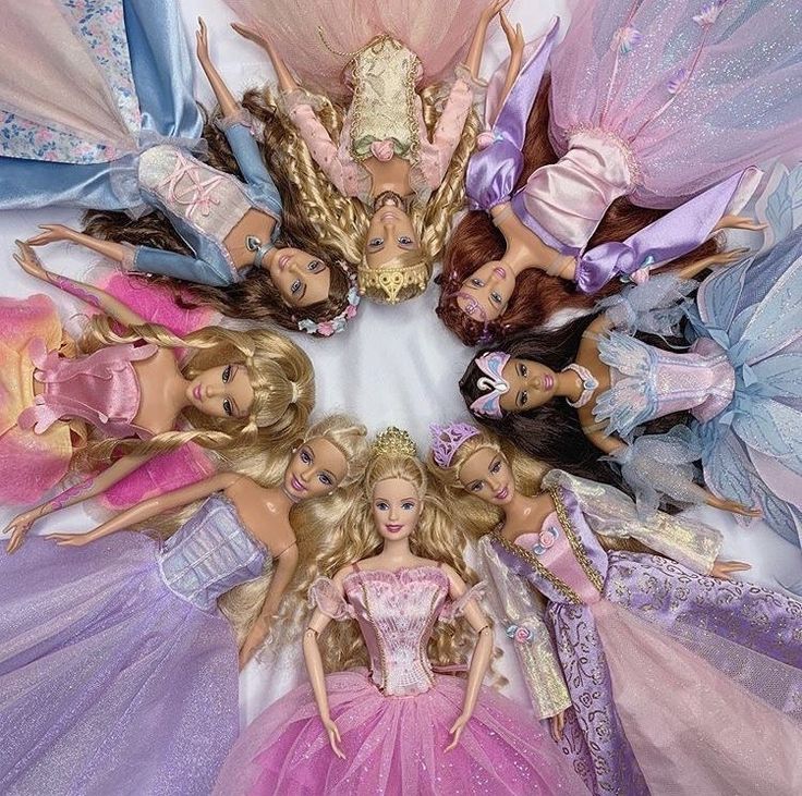 Fashion dolls in pink, blue, and lavender gowns arranged in a circle around one central doll
