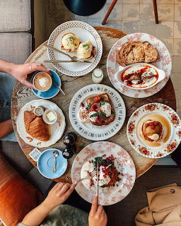Overhead shot of brunch spread with pastries, pancakes, and coffee on white plates