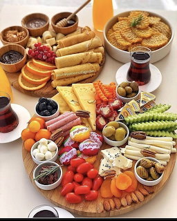 Overhead view of cheese board with crackers, fruits, meats, olives, and condiments arranged on wooden platters