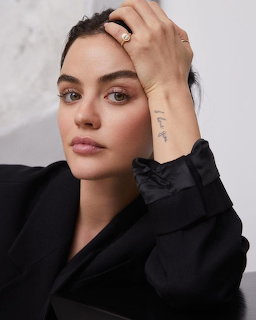 Portrait of woman in black blazer with hand on forehead looking at camera