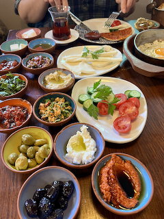 Turkish breakfast spread with small dishes of olives, cheese, tomatoes, cucumbers, eggs, bread, and tea