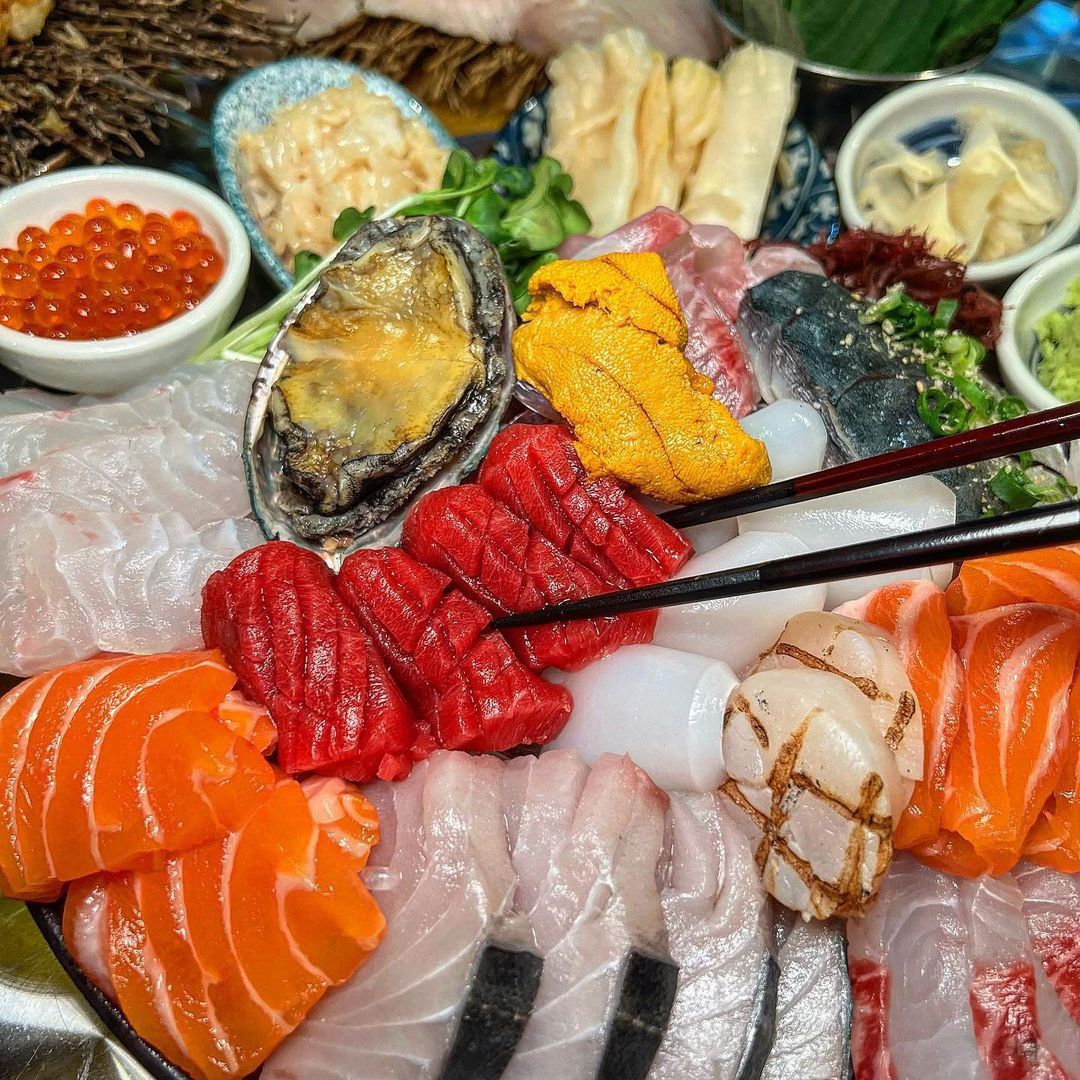 Assorted Japanese sashimi platter with salmon, tuna, octopus, sea urchin, roe, and garnishes arranged on ice