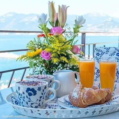 Breakfast tray with croissants, orange juice, coffee and flowers by the sea