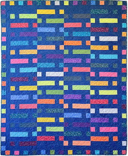 Colorful quilt with bright rectangular strips in various colors arranged in rows on dark blue fabric