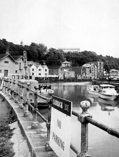 Black and white photo of Truro harbour with boats, waterfront buildings, and a No Parking sign on the quay