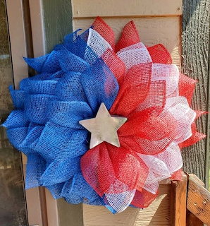 Red white and blue mesh wreath with white star center on wood