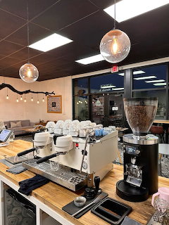 Professional espresso machine and grinder on cafe counter with pendant lights overhead