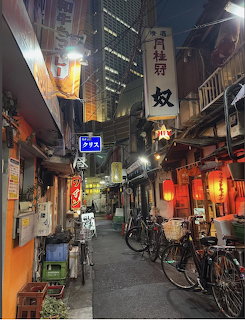 Narrow Japanese alley at night with lanterns, bicycles, and vertical signs