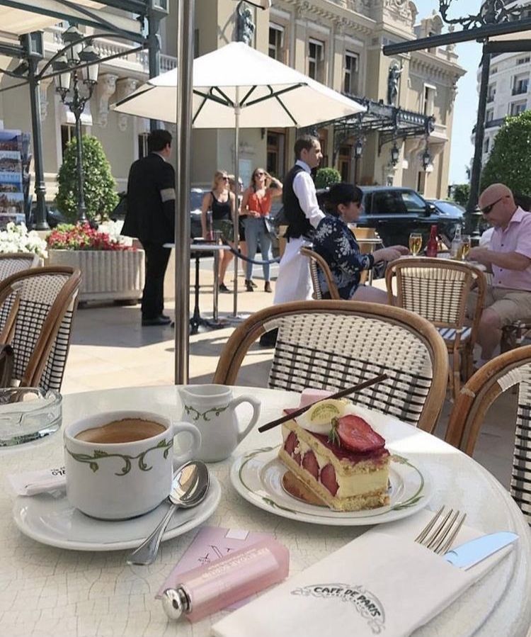 Slice of strawberry cake and coffee on a table at an outdoor cafe
