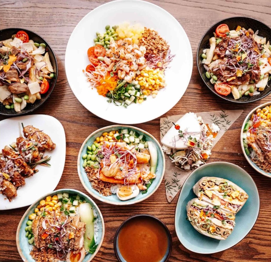 Variety of colorful food bowls with vegetables, grains, and proteins on wooden table