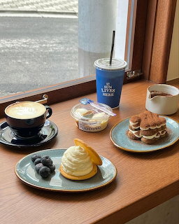 Coffee and assorted desserts on a wooden table by a window