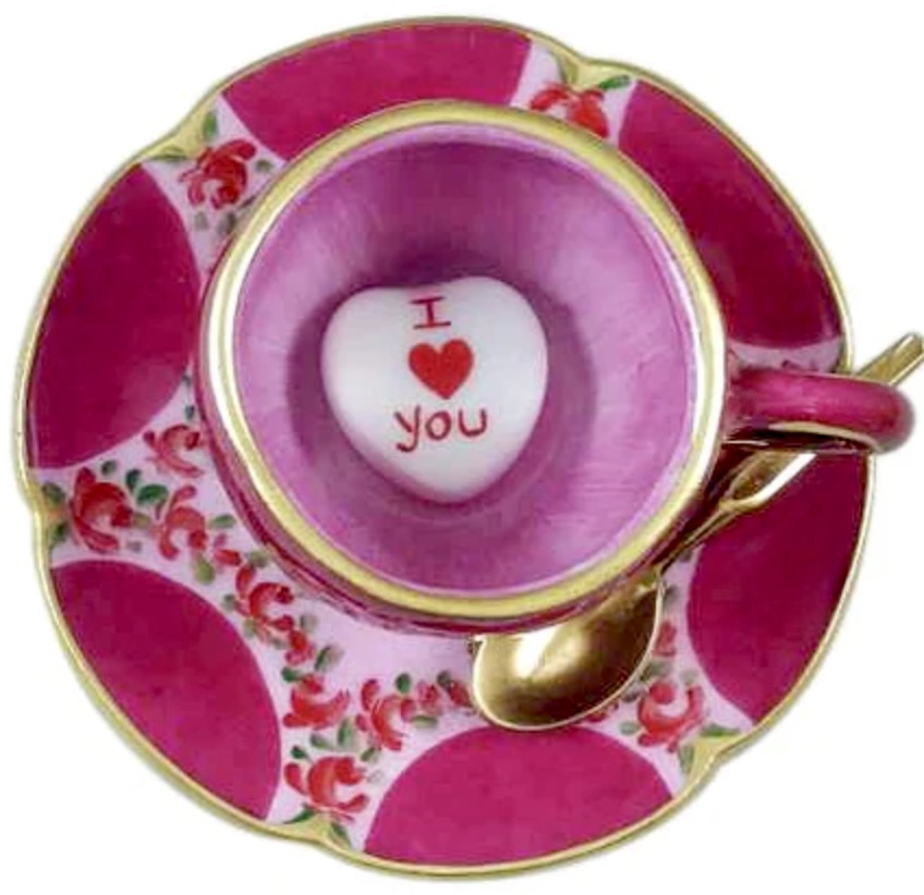 Pink teacup and saucer with heart candy reading 'I love you' and gold spoon