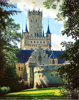 Marienburg Castle in Germany with Gothic towers and blue rofs surrounded by green trees