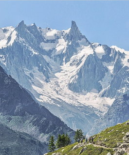Snow-covered jagged mountain peaks with glaciers and alpine forest in Chamonix