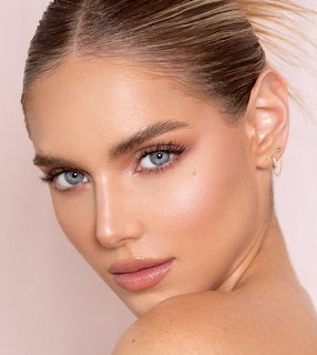 Close-up portrait of blonde woman with blue eyes and natural makeup on pink background