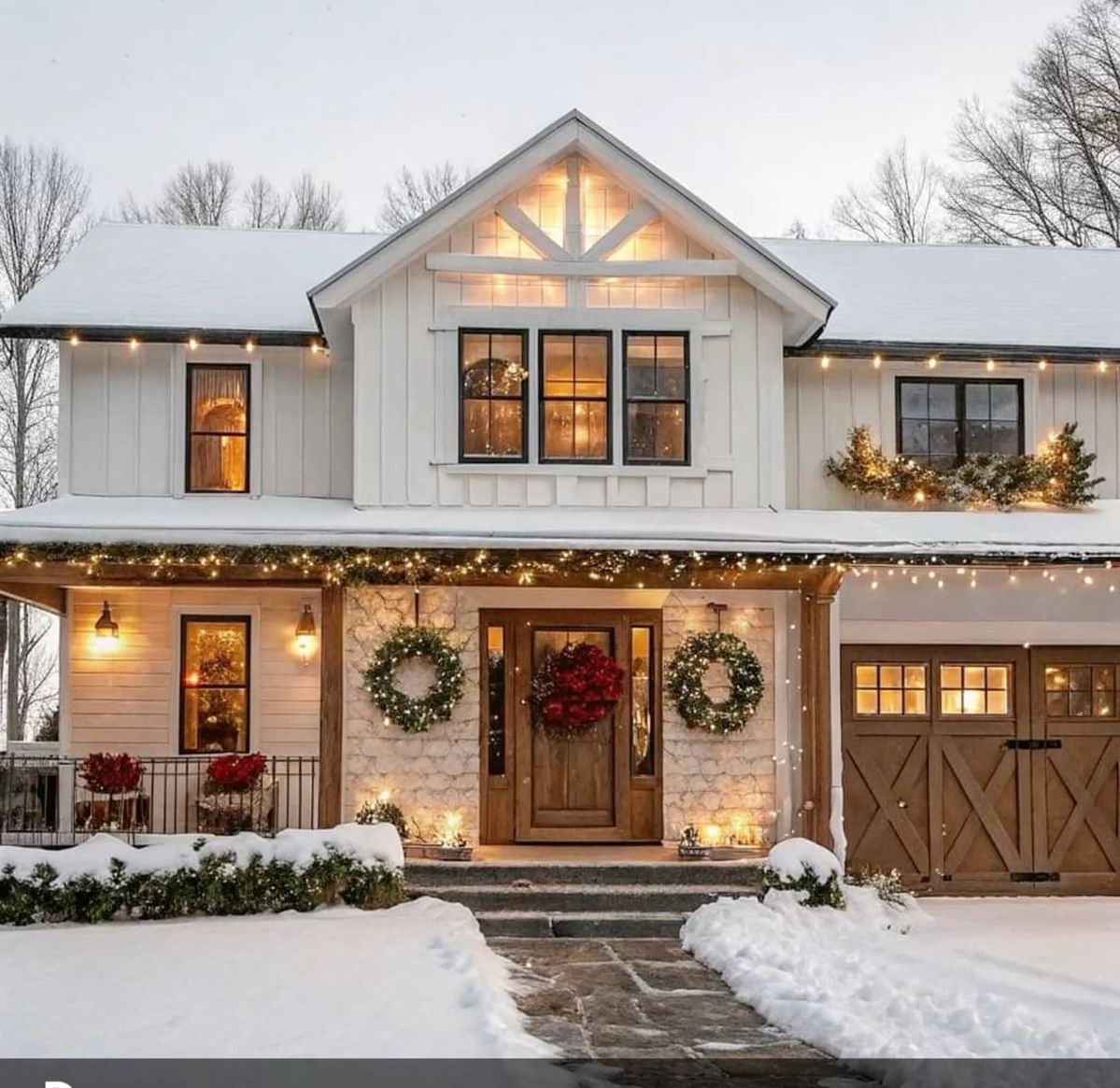 White modern farmhouse with snow-covered front yard and glowing windows at twilight
