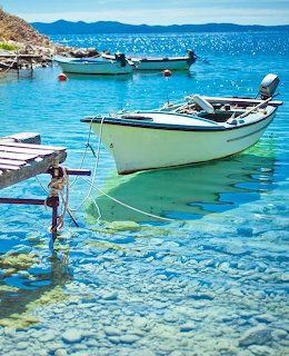 White motorboat anchored in clear turquoise water with pebble bottom and other boats in background