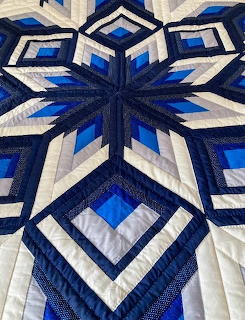 Blue and white Amish snowflake quilt with geometric star pattern and diamond shapes