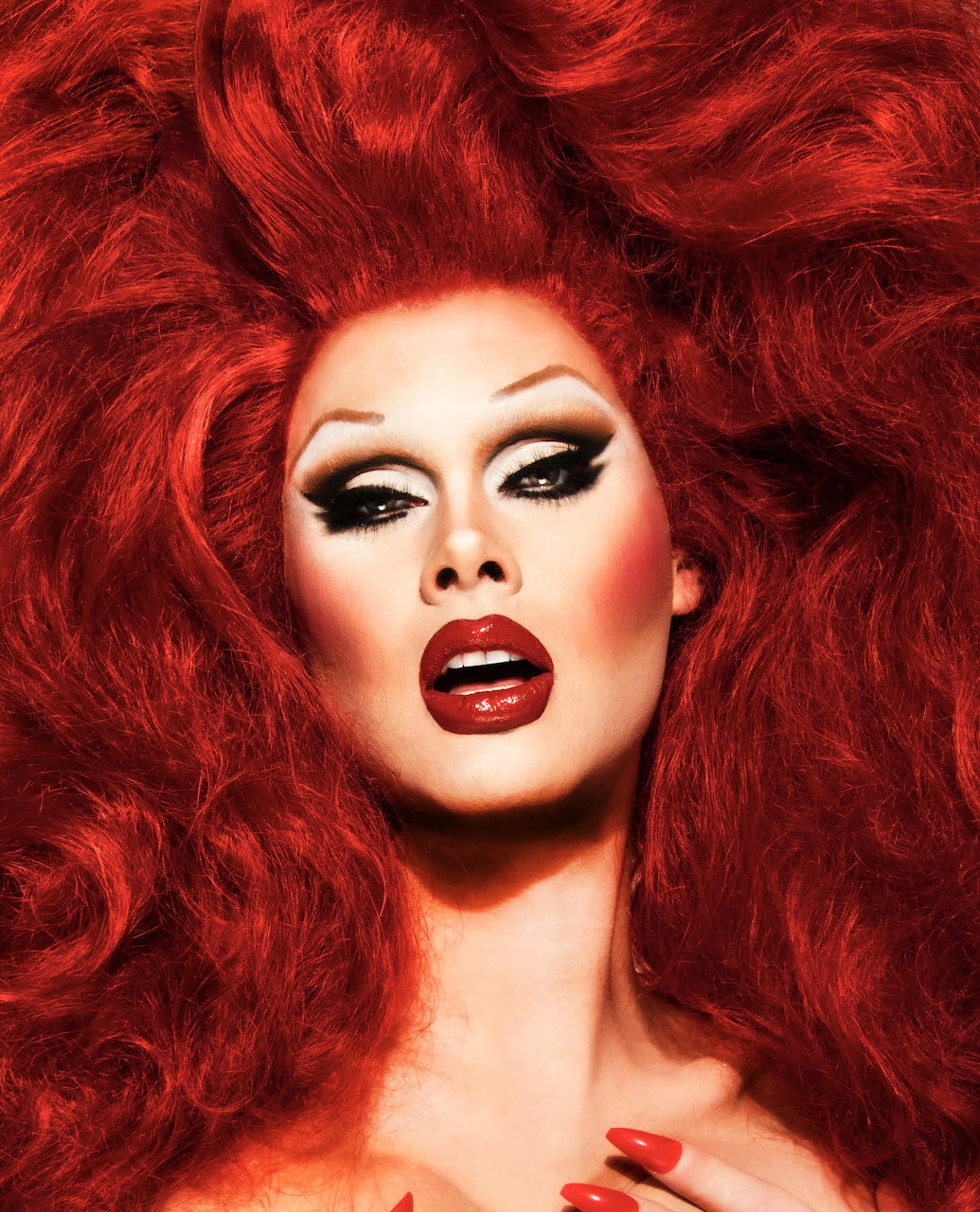 Drag queen Scarlet Envy with voluminous red hair and glamorous makeup