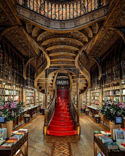 Grand historic bookstore with red staircase, wooden shelves, and ornate ceiling
