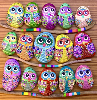 Fifteen hand-painted rocks decorated as colorful owls with detailed patterns arranged in three rows