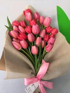 Bouquet of pink tulips wrapped in beige paper with a pink ribbon bow
