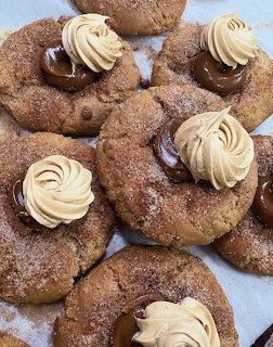 Cinnamon sugar cookies topped with piped buttercream frosting and chocolate ganache on parchment paper