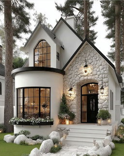 White cottage house with stone facade, arched windows, and entrance steps surrounded by pine trees