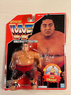 Packaged wrestler action figure on a red blister card with portrait artwork