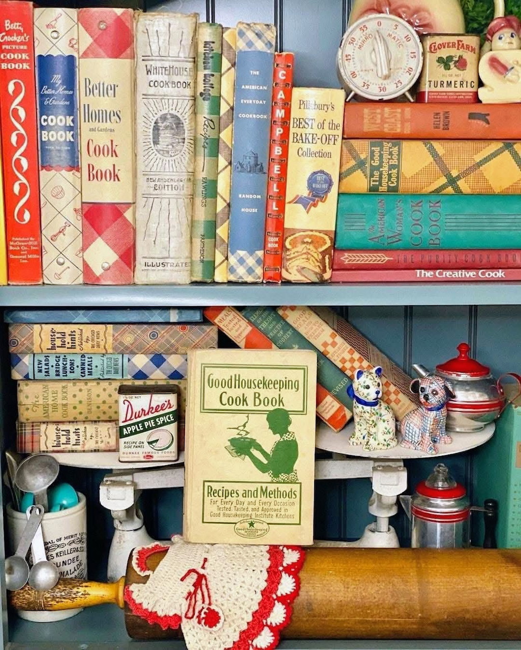 Vintage cookbooks and kitchen utensils displayed on blue wooden shelves