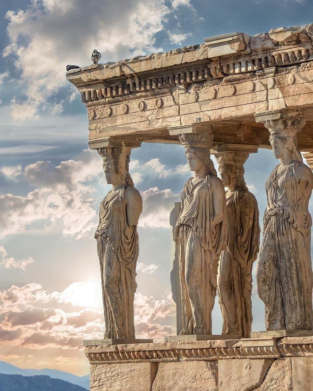 Caryatid statues on the Erechtheion temple porch in Athens, Greece, with a cloudy sky