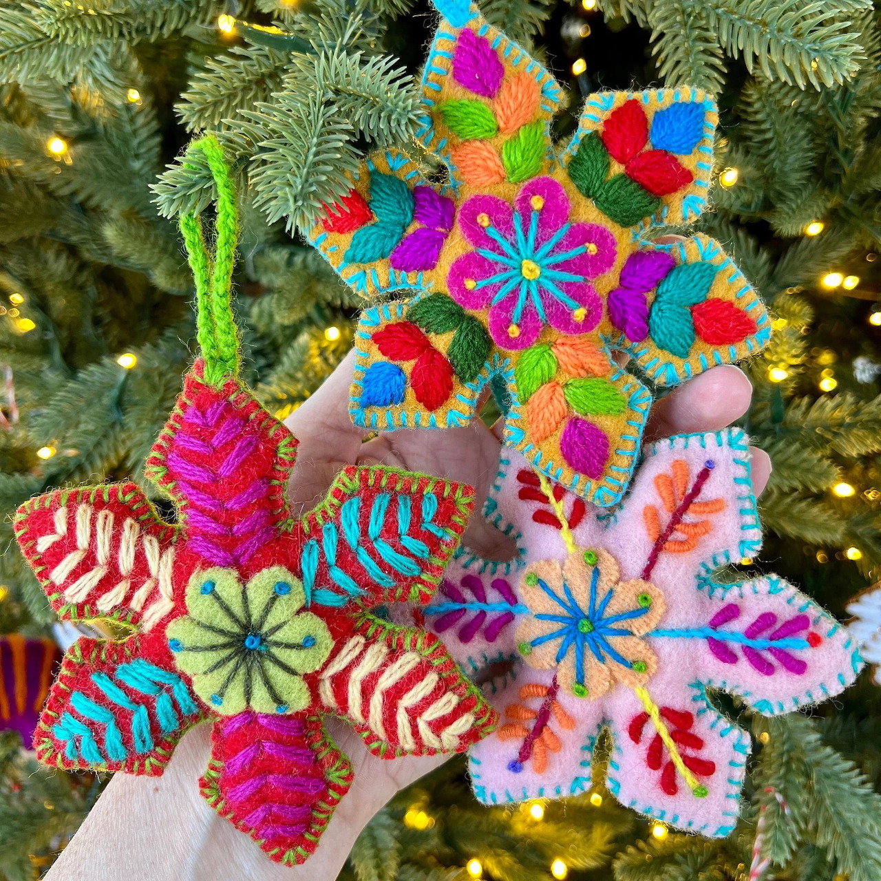 Handmade felt Christmas ornaments with colorful embroidered patterns on tree