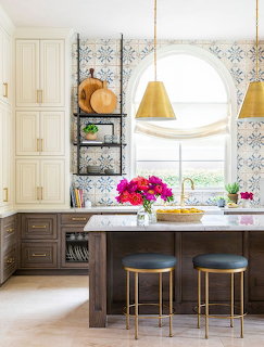 Bright kitchen with an arched window, island, stools, pendant lights, and flowers