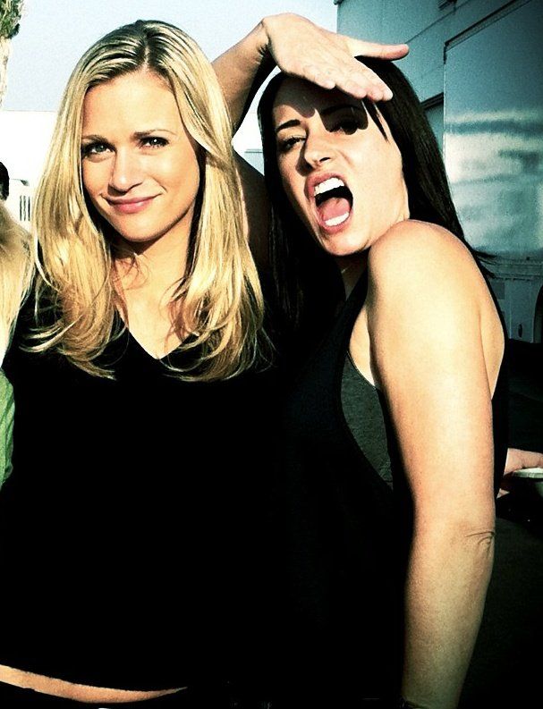 Blonde woman and dark-haired woman laughing and posing together outdoors