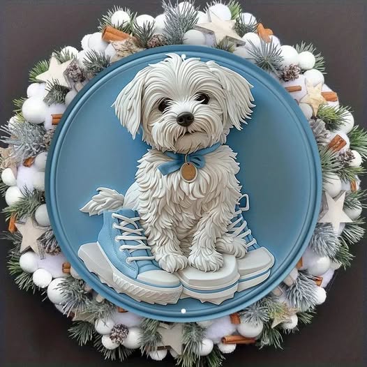 White Maltese dog sitting in blue sneakers inside a snowy winter wreath