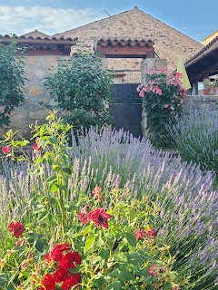 Rustic stone building entrance with vibrant garden of lavender, roses and flowers in Spanish village