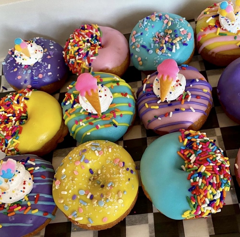 Colorful donuts with pastel frosting, sprinkles, and Easter egg decorations arranged in rows