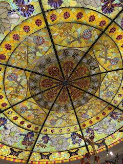 Detailed stained glass dome with radial geometric pattern and colorful floral motifs viewed from below