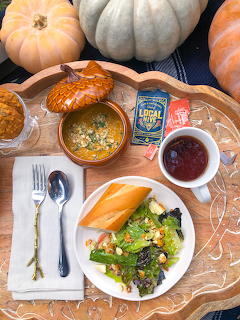 Autumn meal with pumpkin soup, salad, bread, and decorative pumpkins on wooden table