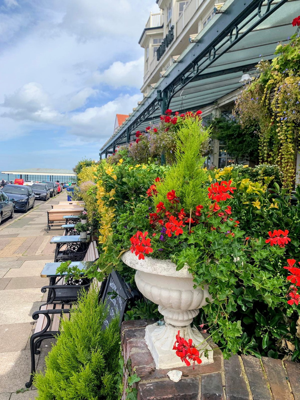 Hotel terrace with white stone urns filled with red geraniums and green plants, sea visible in background, Cliftonville Kent