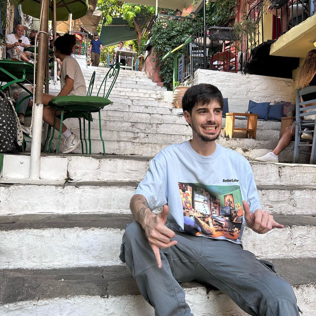Smiling man sitting on outdoor stone steps in a narrow street