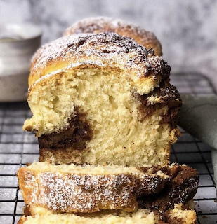 Sliced sweet bread loaf with powdered sugar on a cooling rack