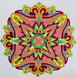 Colorful symmetrical mandala with intricate geometric patterns in vibrant rainbow hues on gray background
