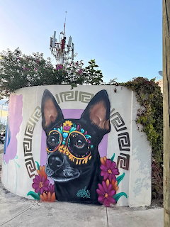 Street mural showing a black dog with Day of the Dead sugar skull face paint and floral decorations
