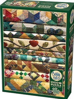 Stack of colorful folded patchwork quilts with various patterns including stars, hearts, and leaves