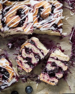 Blueberry cake bars with white icing drizzle on parchment paper